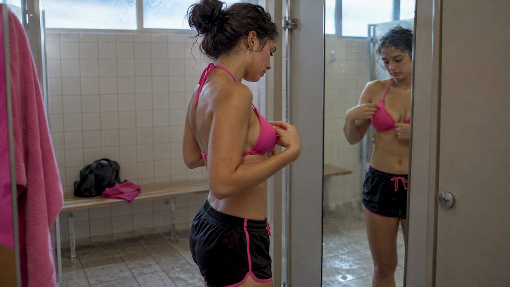 Woman checking bikini top fit in mirror